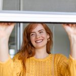 Woman hand hold retractable pleated insect screen holder to open or close the window ,mosquito nets